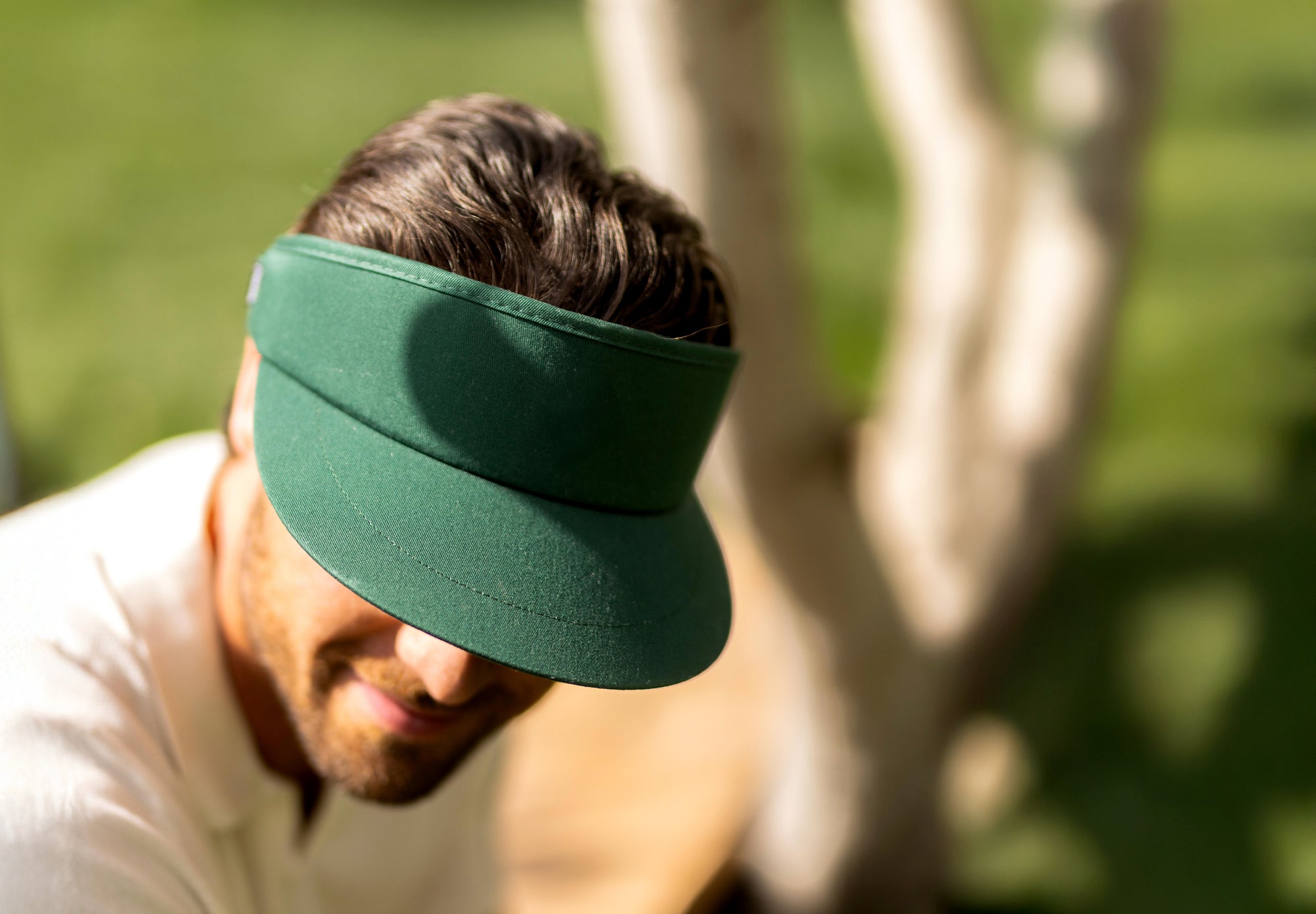 Man wearing a green tour visor outdoors with blurred background